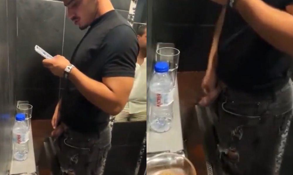 Handsome guy pissing and spitting at urinals